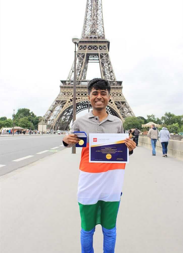 Drone boy Pratap standing in front of the Eiffel Tower with the award